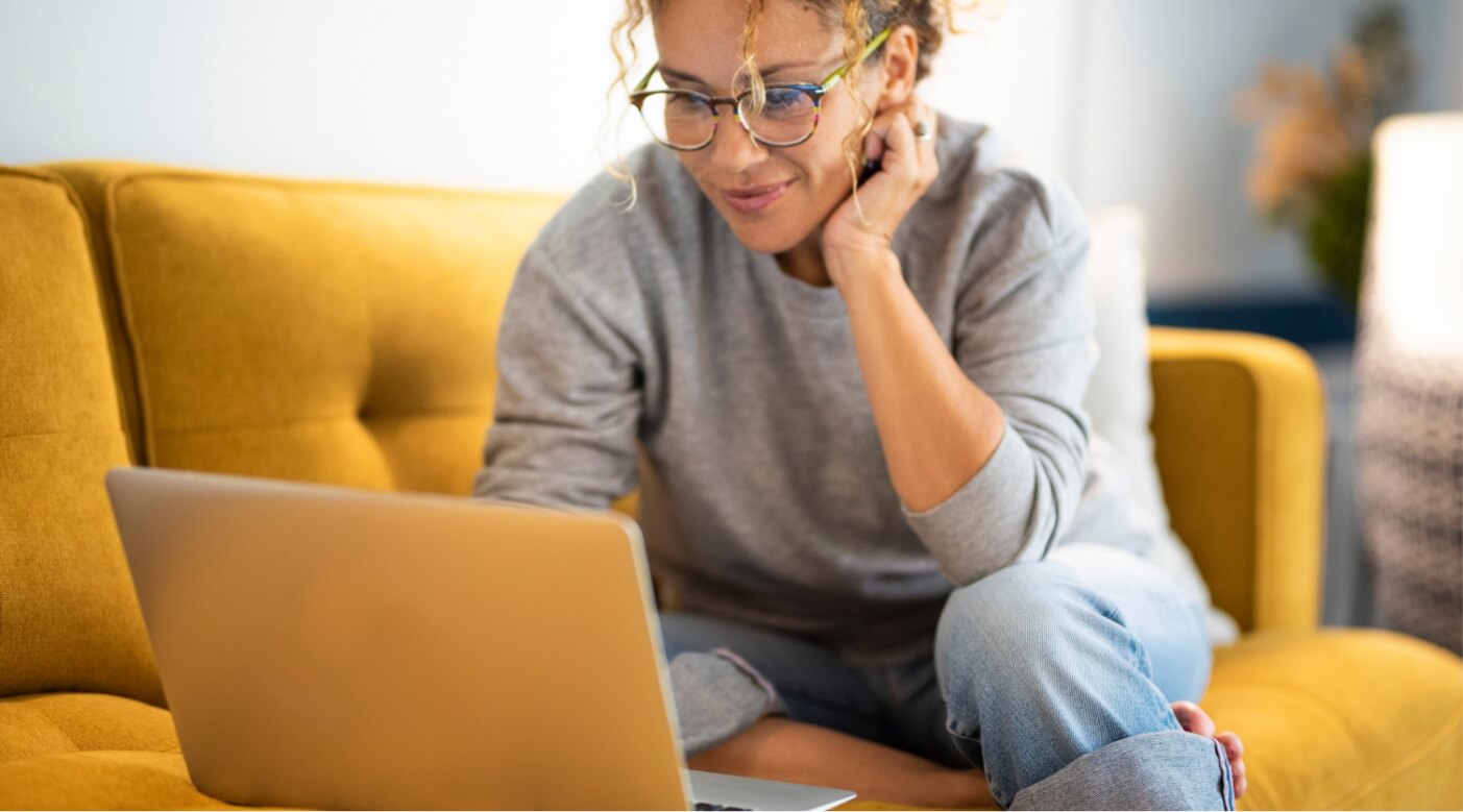 Woman sitting on couch looking at laptop