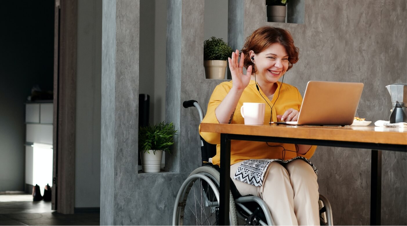 girl in wheelchair waving at laptop screen
