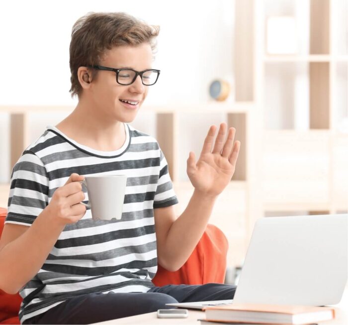 boy holding up hand in front of laptop