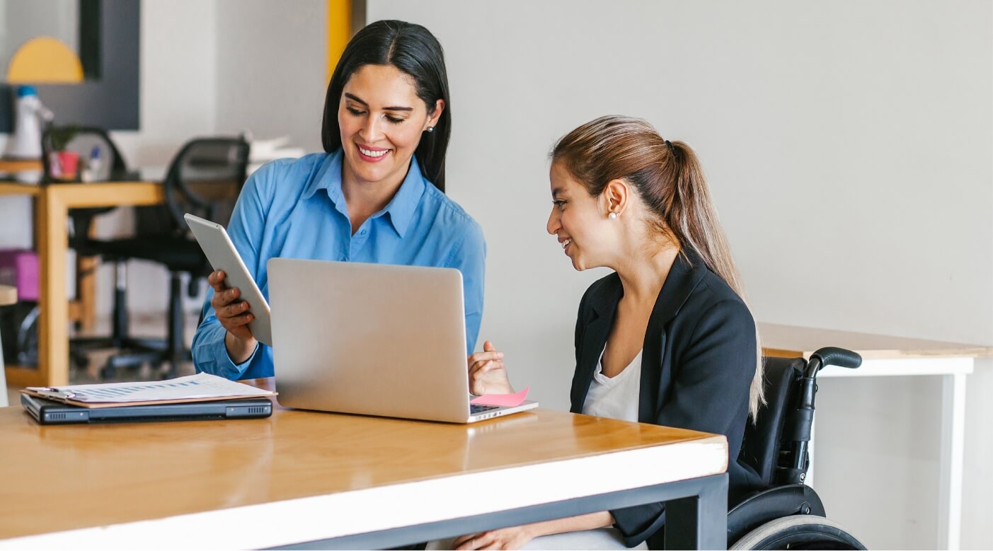 woman in wheelchair looking at co workers tablet screen