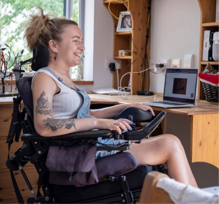 woman in wheelchair turning head in front of laptop