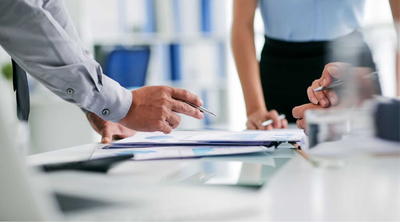 people in business meeting pointing at paperwork